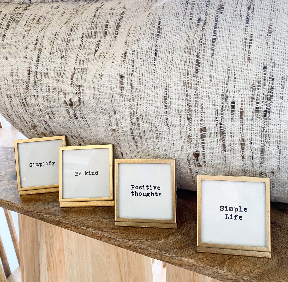 small gold frames lined up on a shelf with sayings written on them