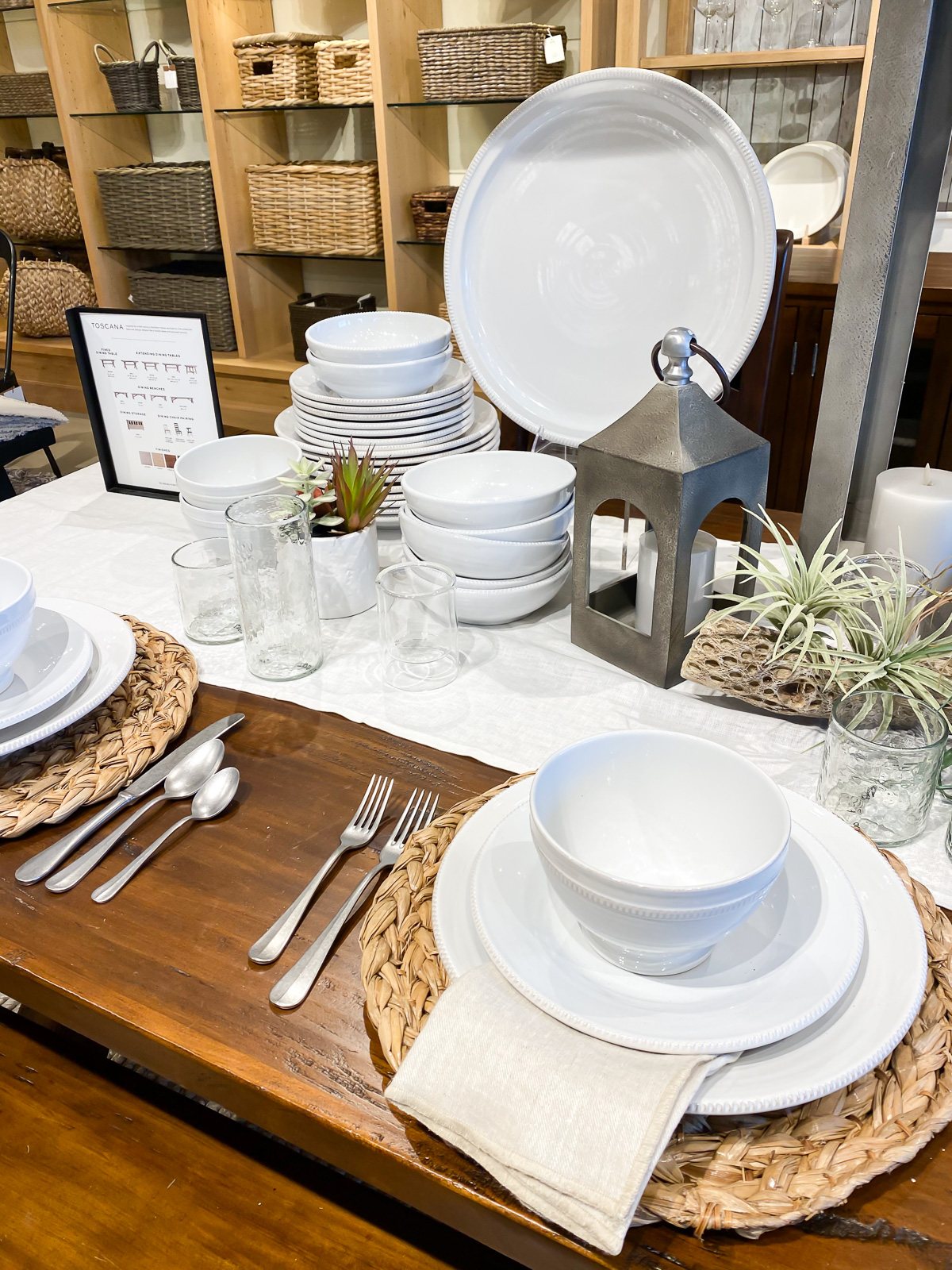 White table place settings in wood table in Pottery Barn store.
