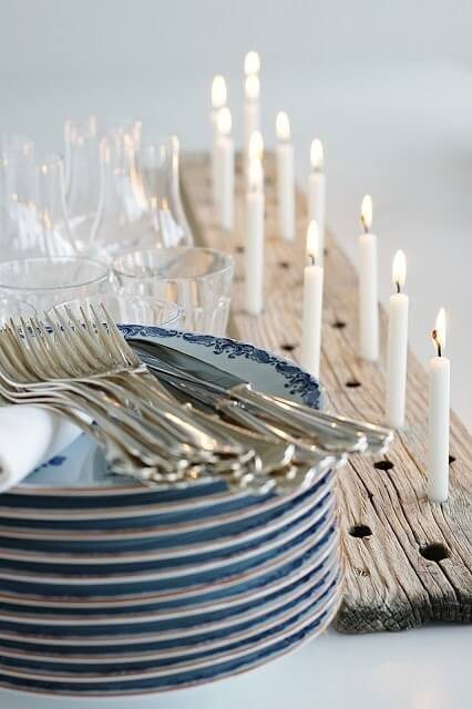 Stack of plates and utensils with a wood plank candle holder