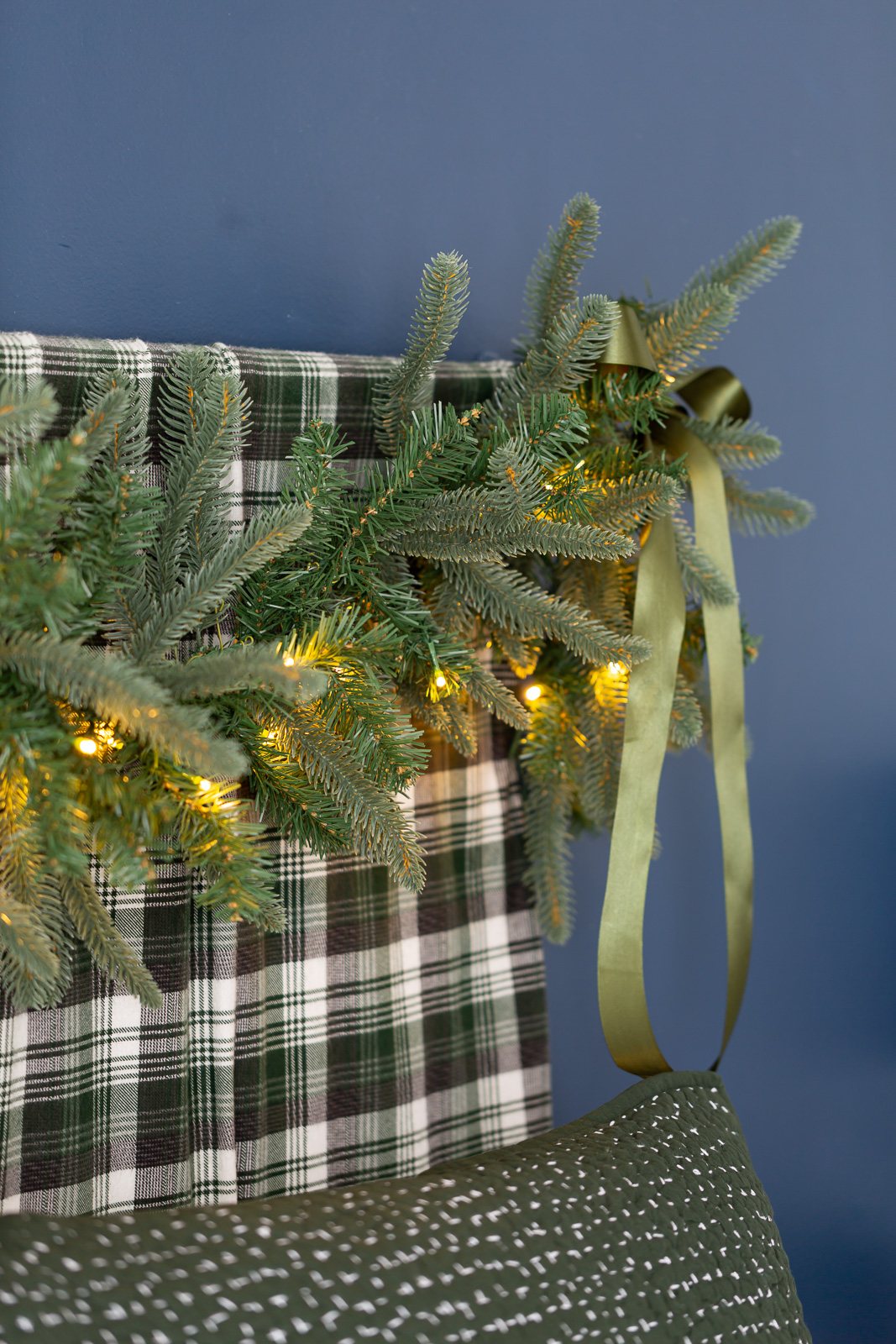 Bed headboard decorated for Christmas using a lit King of Christmas Noble Fir garland.