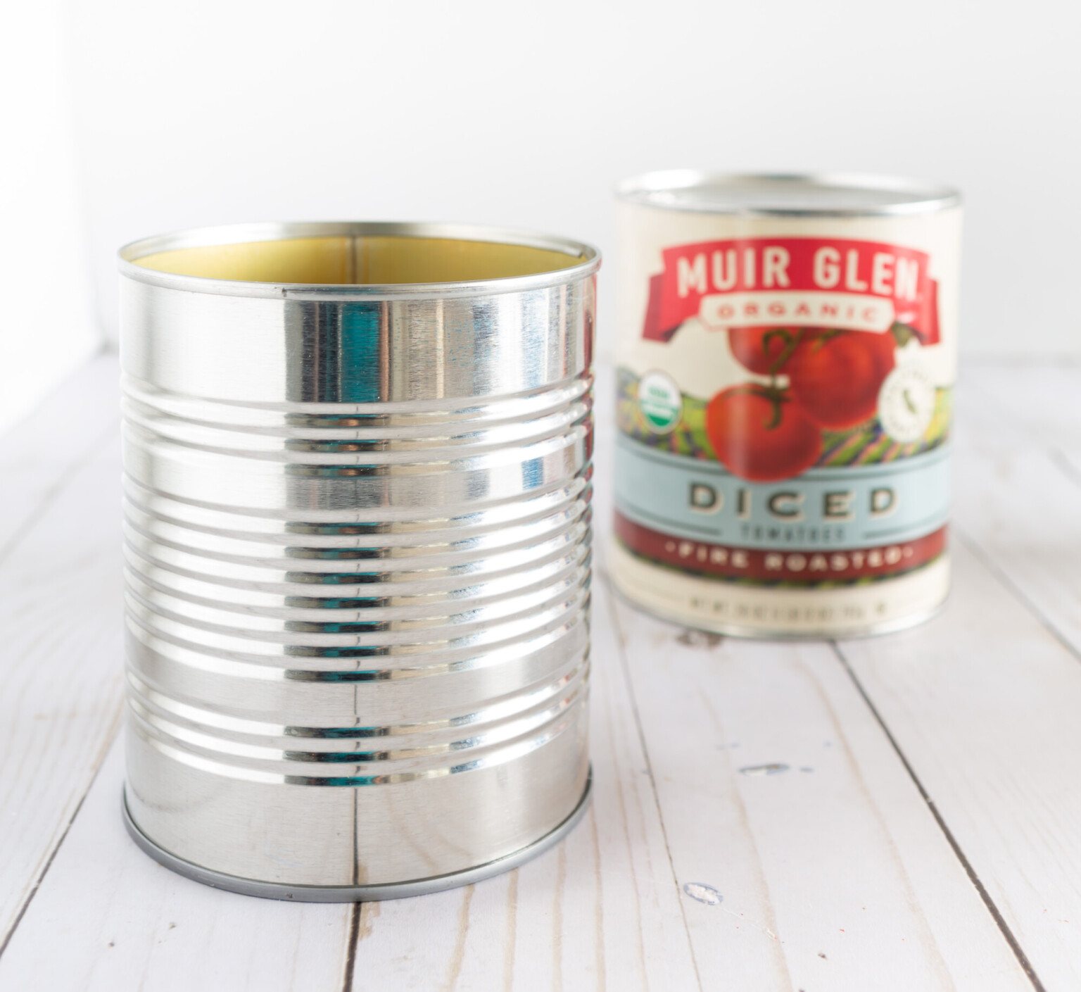 Tin can shown with the paper label off next to one that still has the label.