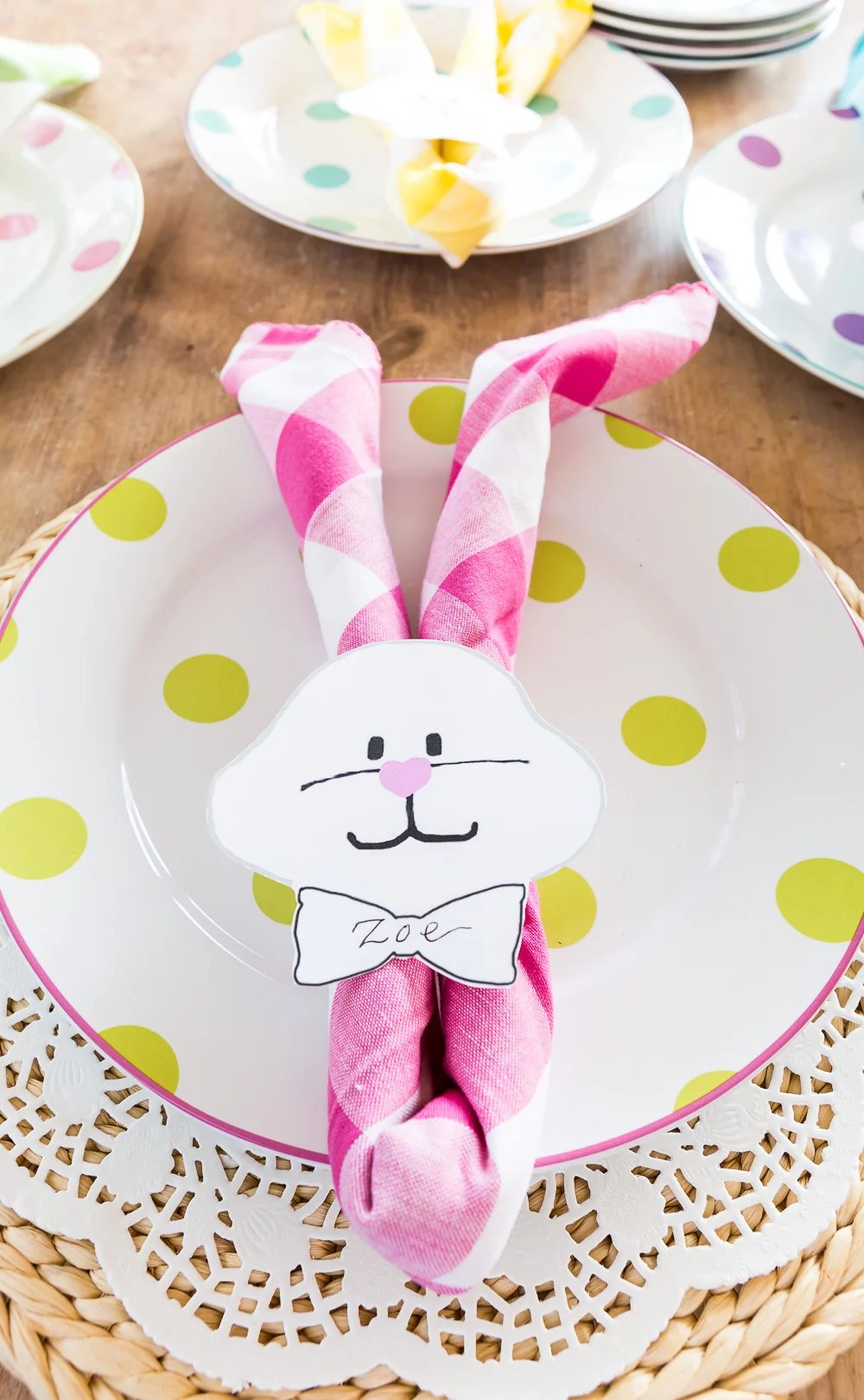 Pastel Pink Buffalo Check Napkin folded to make an Easter bunny napkin holder on a plate.