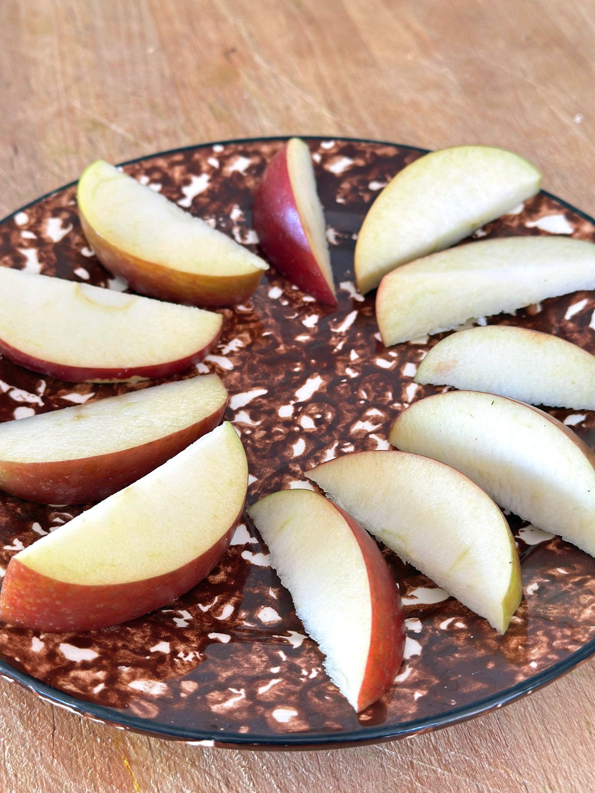 apples displayed on a brown and white plate