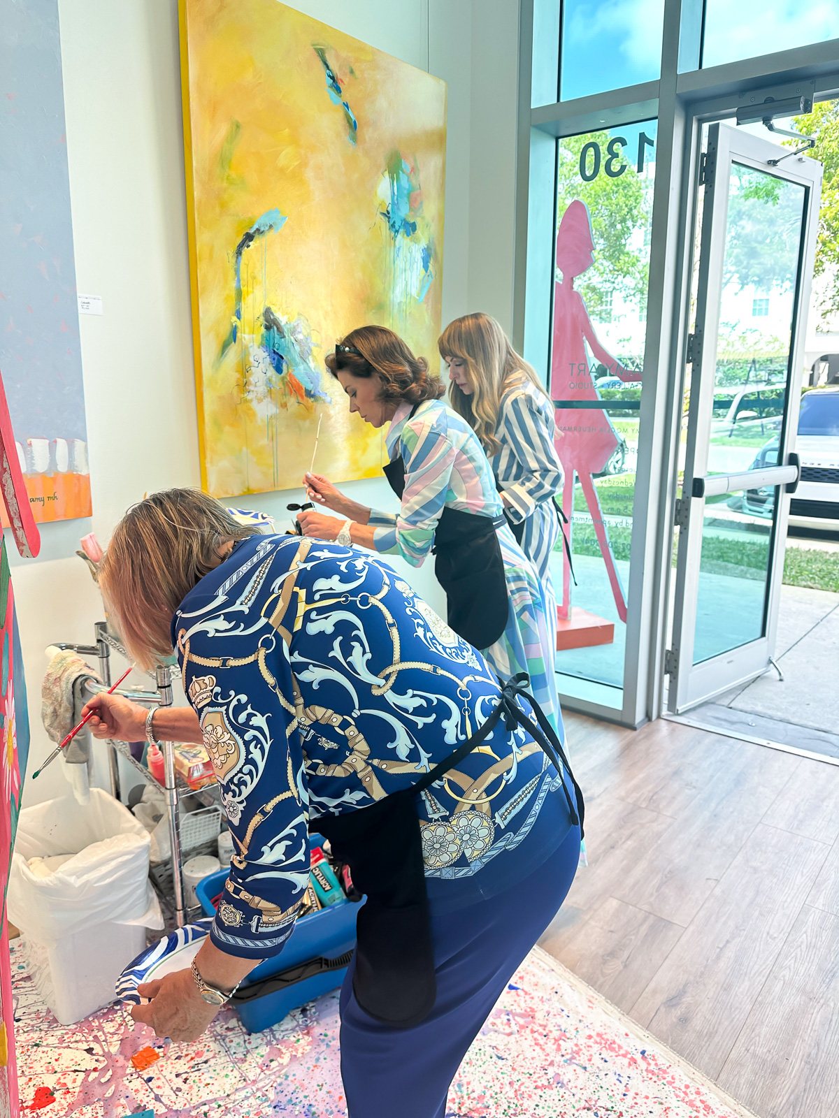 women painting a paper doll sculpture at a charity event at an Art Gallery.