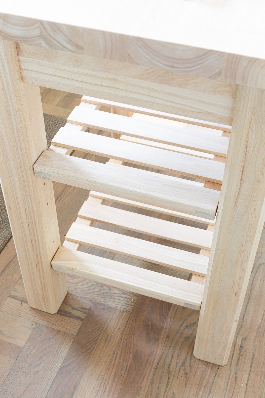 Looking down at the two slat shelves on small wood kitchen island before getting painted.