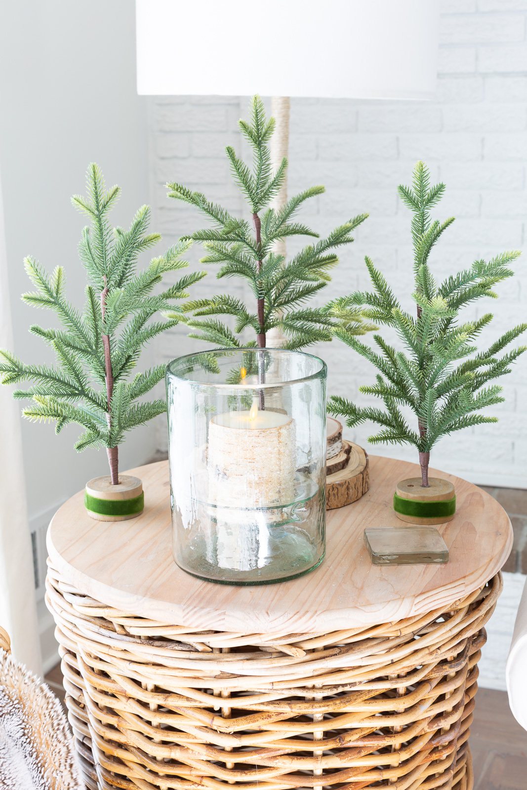 a tabletop with 3 min faux pine trees and a candle