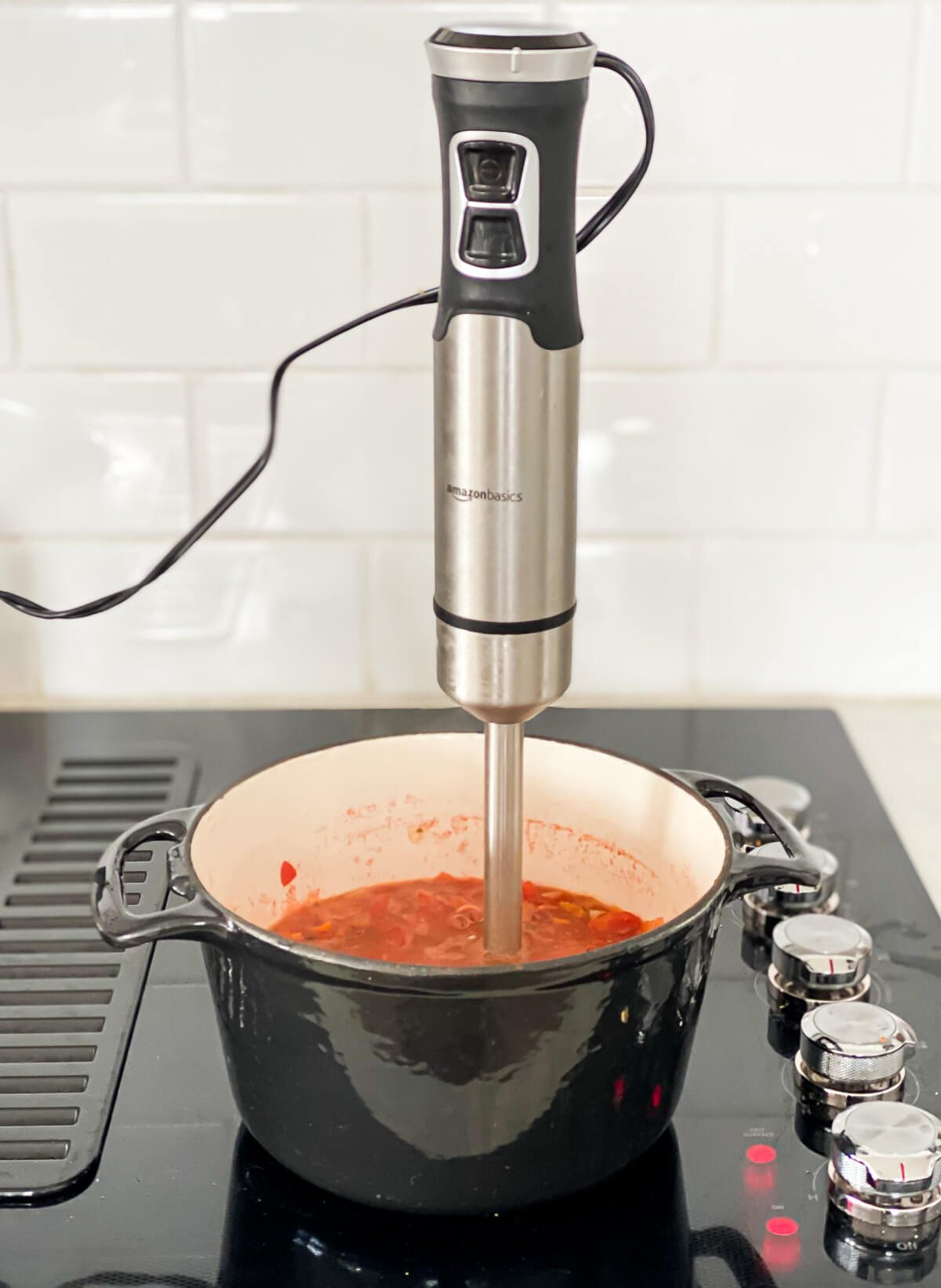 an immersion blender in a soup pot that is cooking on a stove