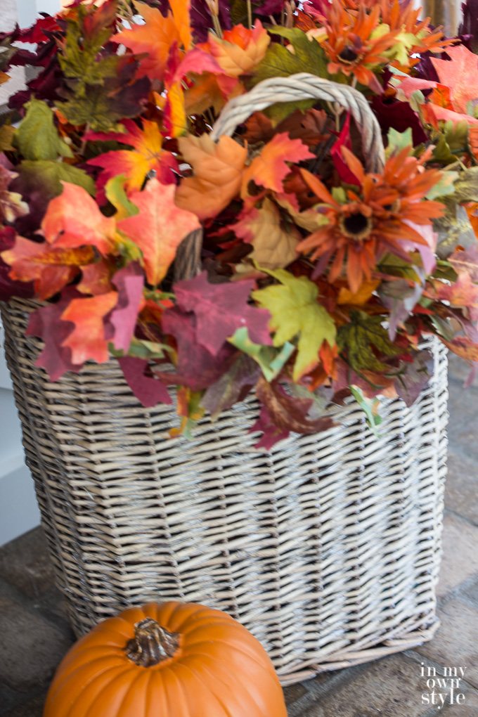 Tall vintage basket filled with fall flowers used to decorate for fall.