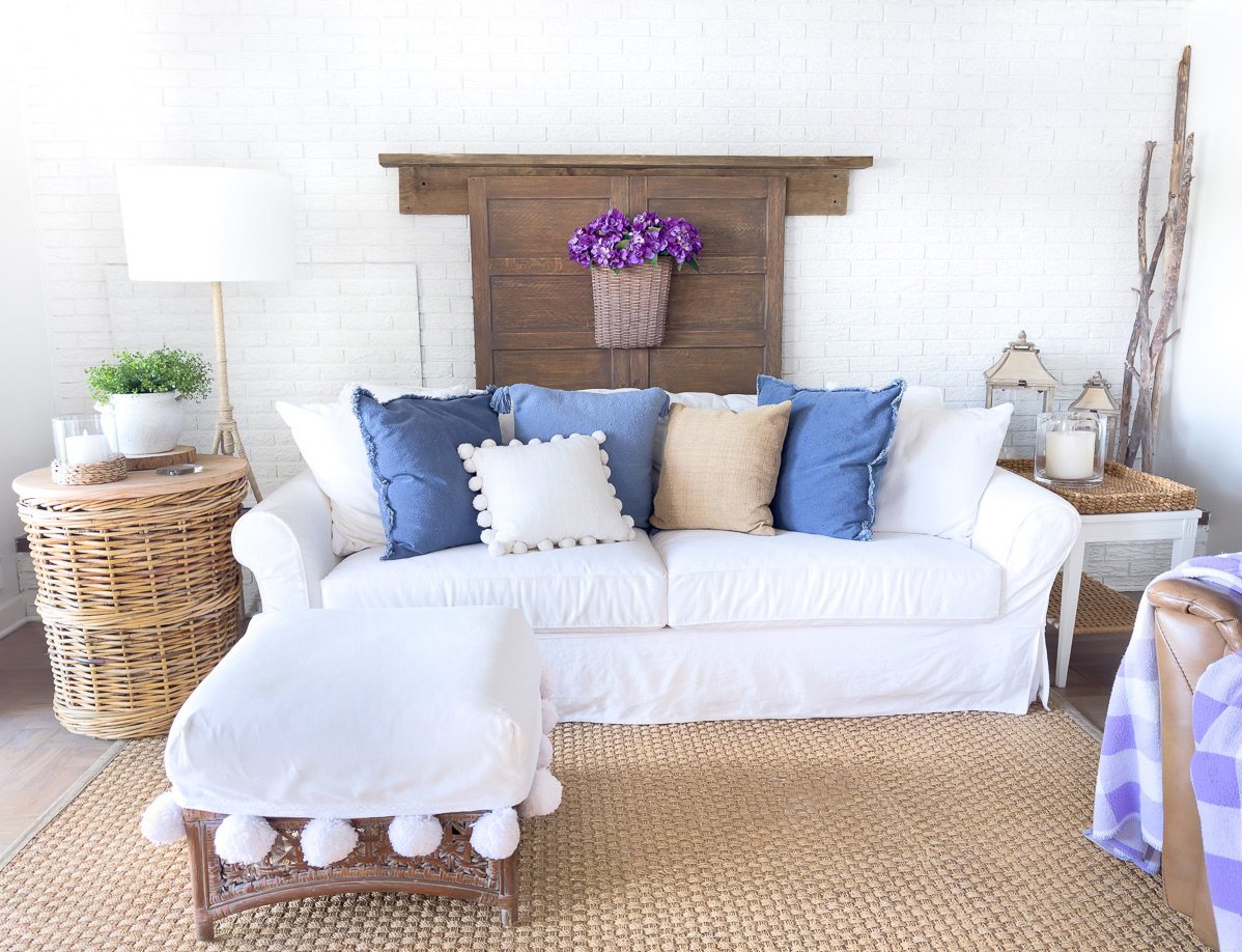 white and blue decorated living room for summer with a white painted brick accent wall.