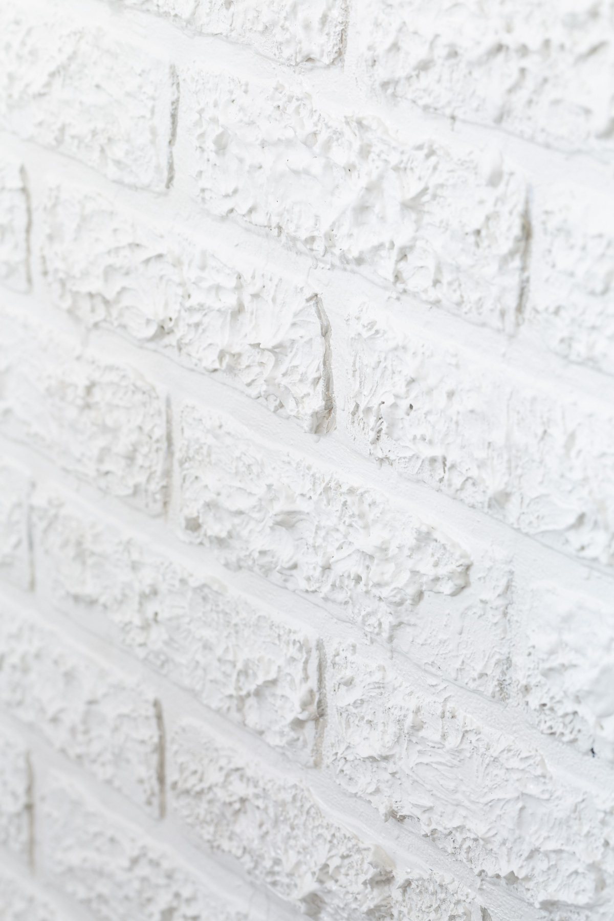 close up of faux brick paneling with spackle added to provide texture to match brick wall around it.