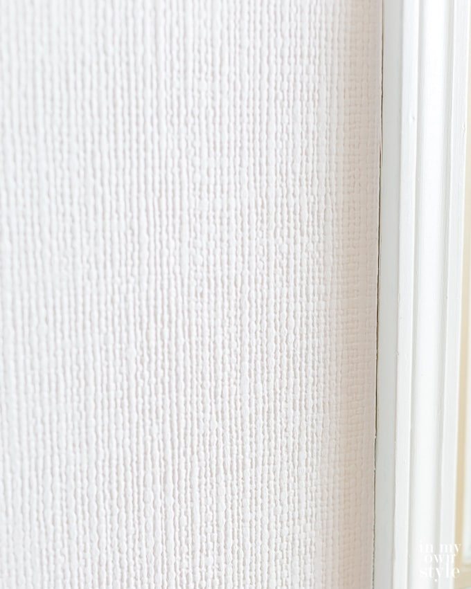 close up photo showing white textured wallpaper on a wall in a kitchen.
