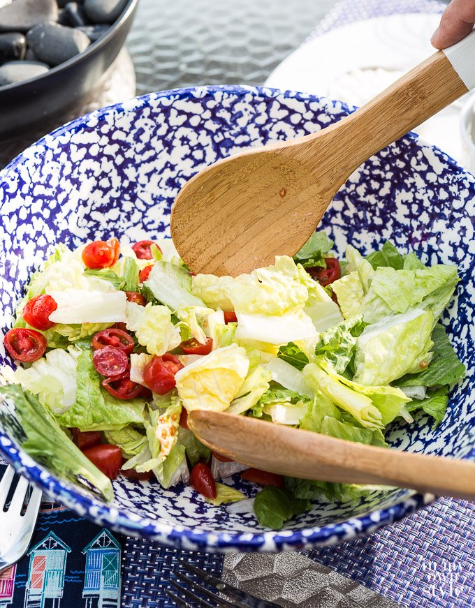 Mixing salad dressing into lettuce with a wooden spoon.