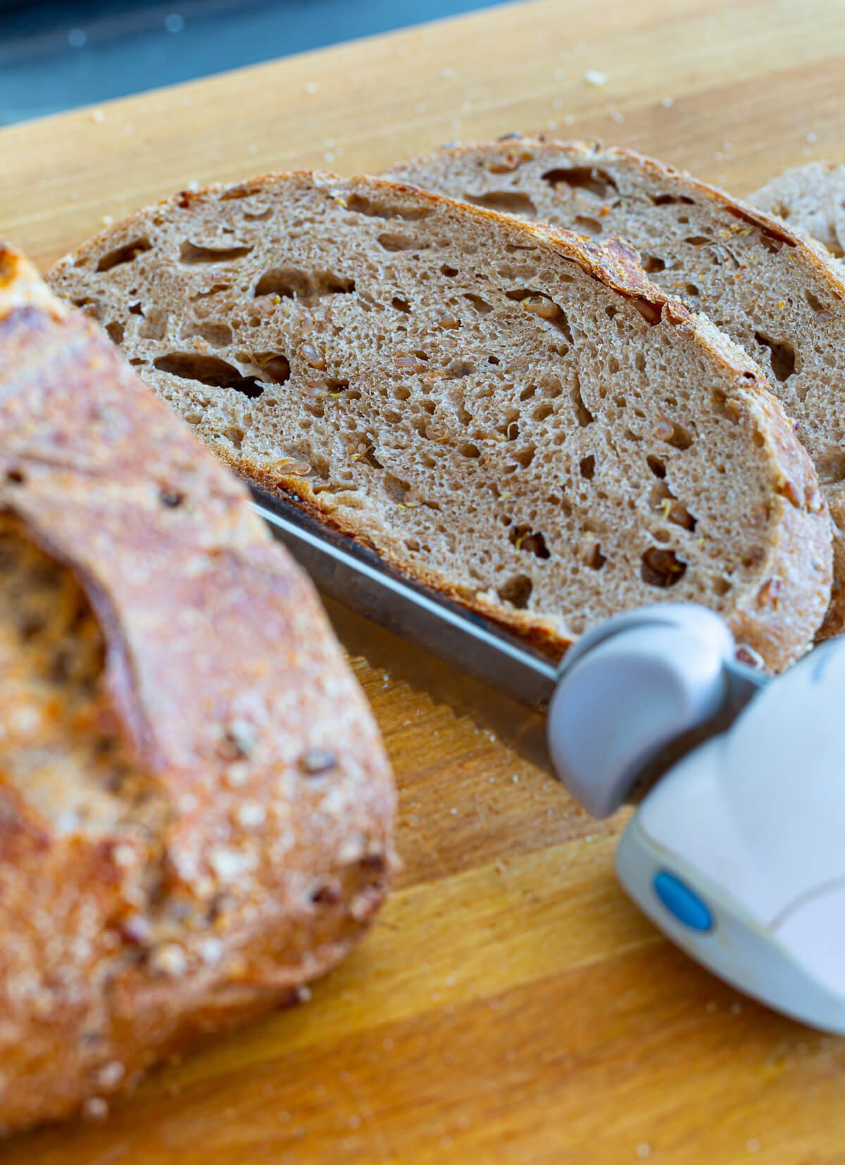 Sourdough bread being cut on a wood cutting board.