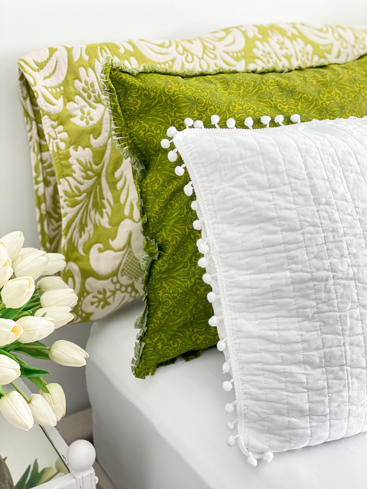 3 green and white bed pillows on a bed