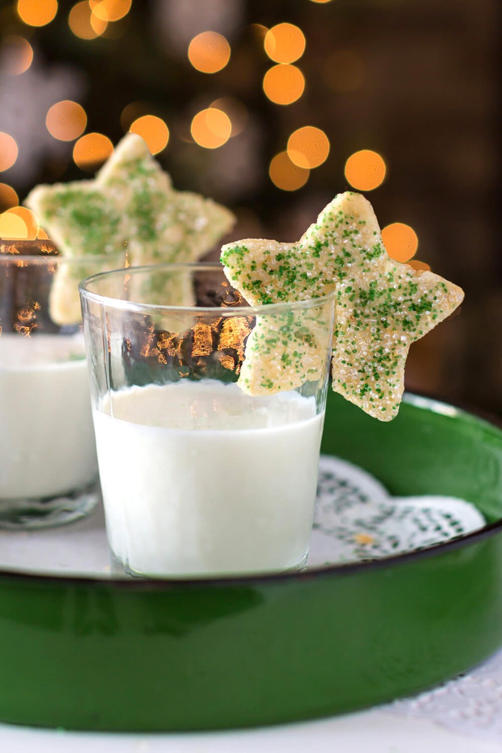 2 star Christmas cookies on the rims of glasses of milk.