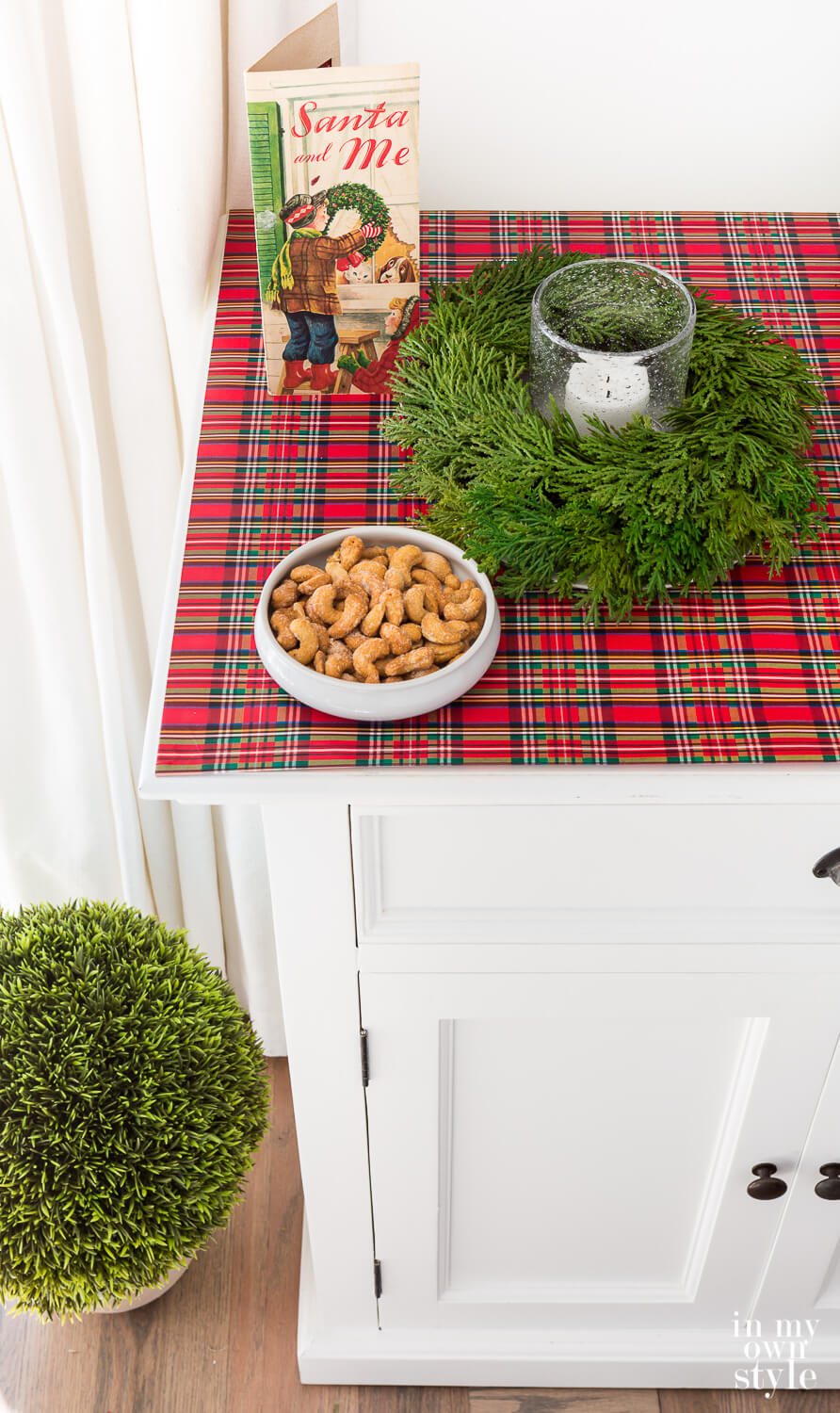 Plaid giftwrap covering the top of a sideboard is one affordable Christmas decorating idea.