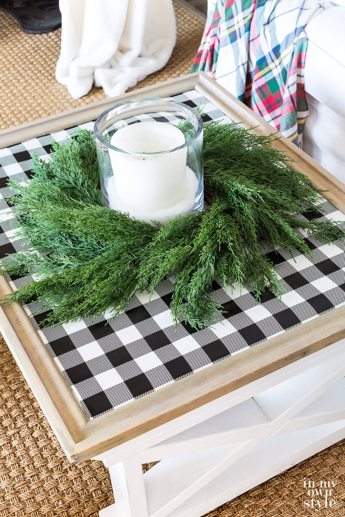Farmhouse coffee table decorated for Christmas with black and white checked gift wrap on table top with cedar wreath and candle.