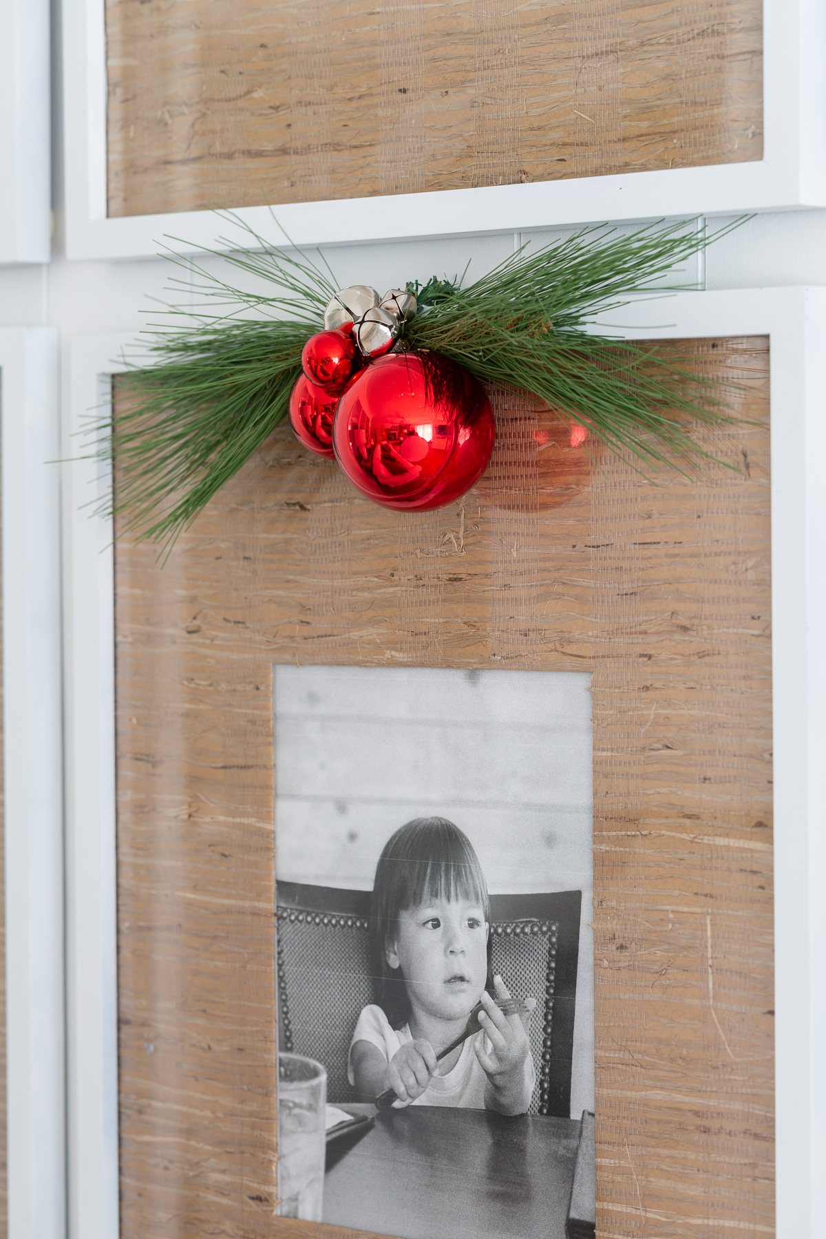 red ball ornaments and greenery hanging on a framed photo