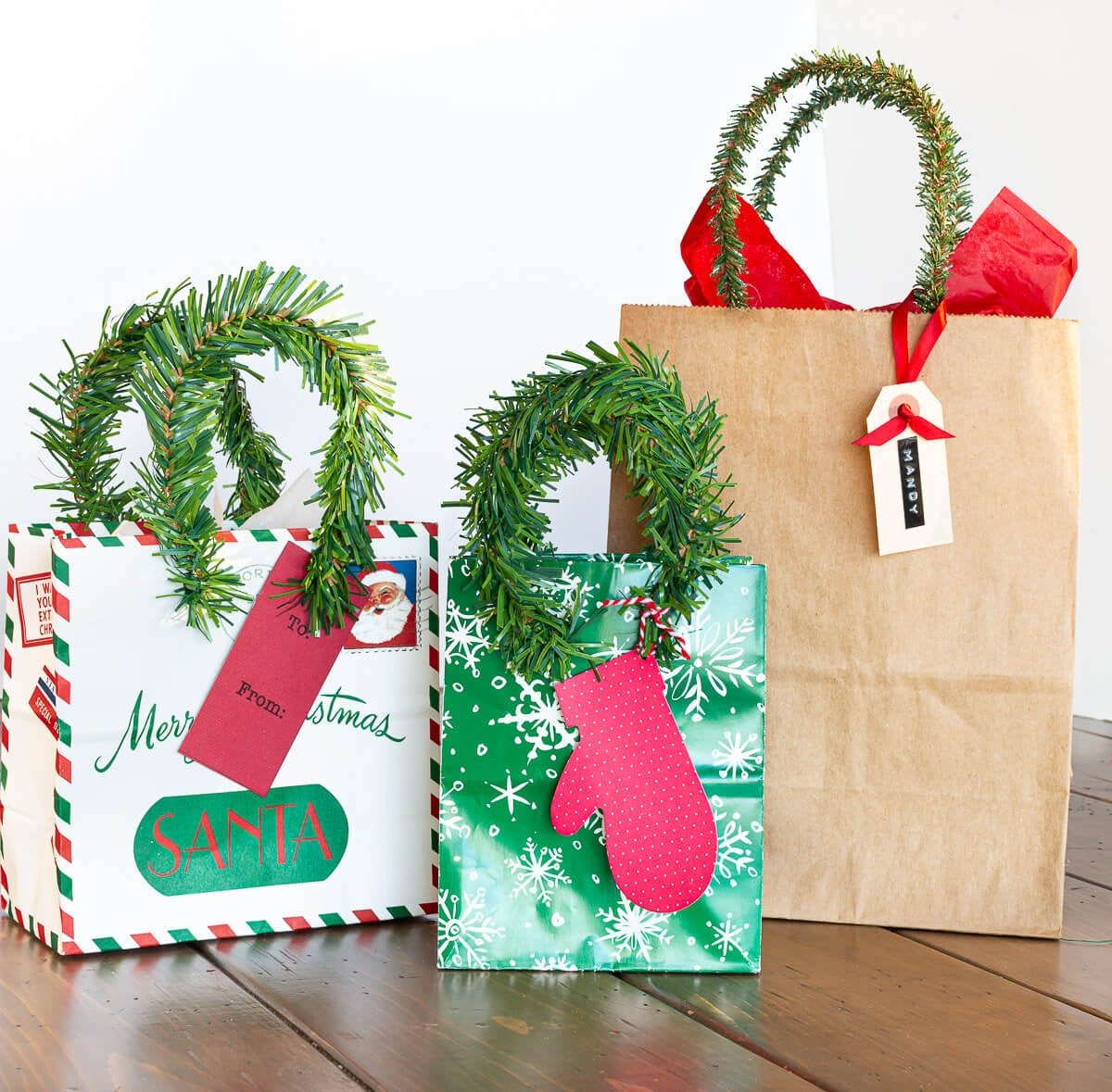 3 Christmas gift bags with new handles made using pine garland ties.