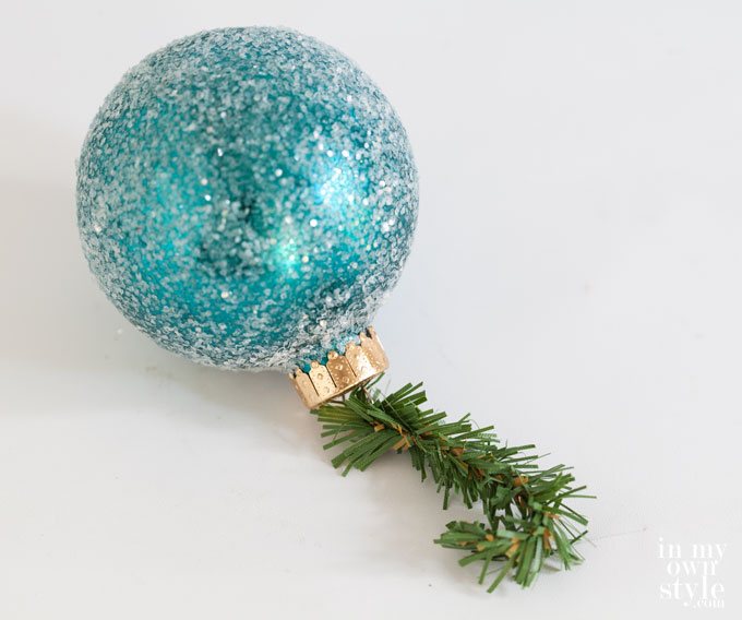 Turquoise glittered ball ornament with a pine branch ornament hook.