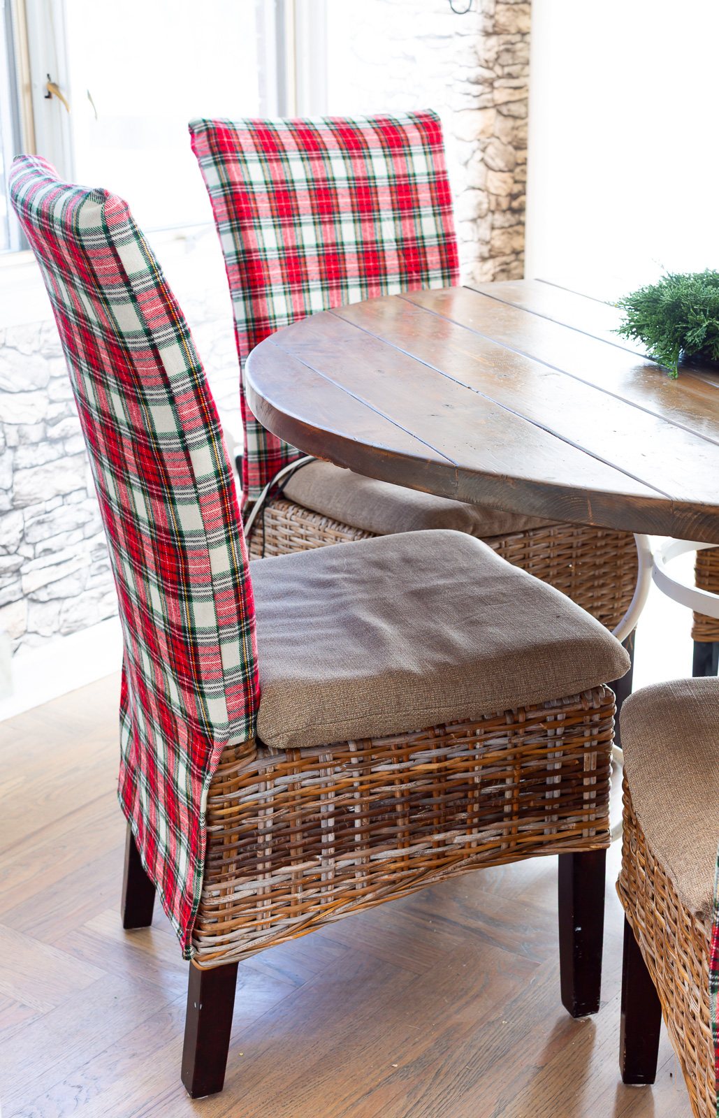 Looking at side of a holiday plaid covered dining chair as it sits around a dining table.