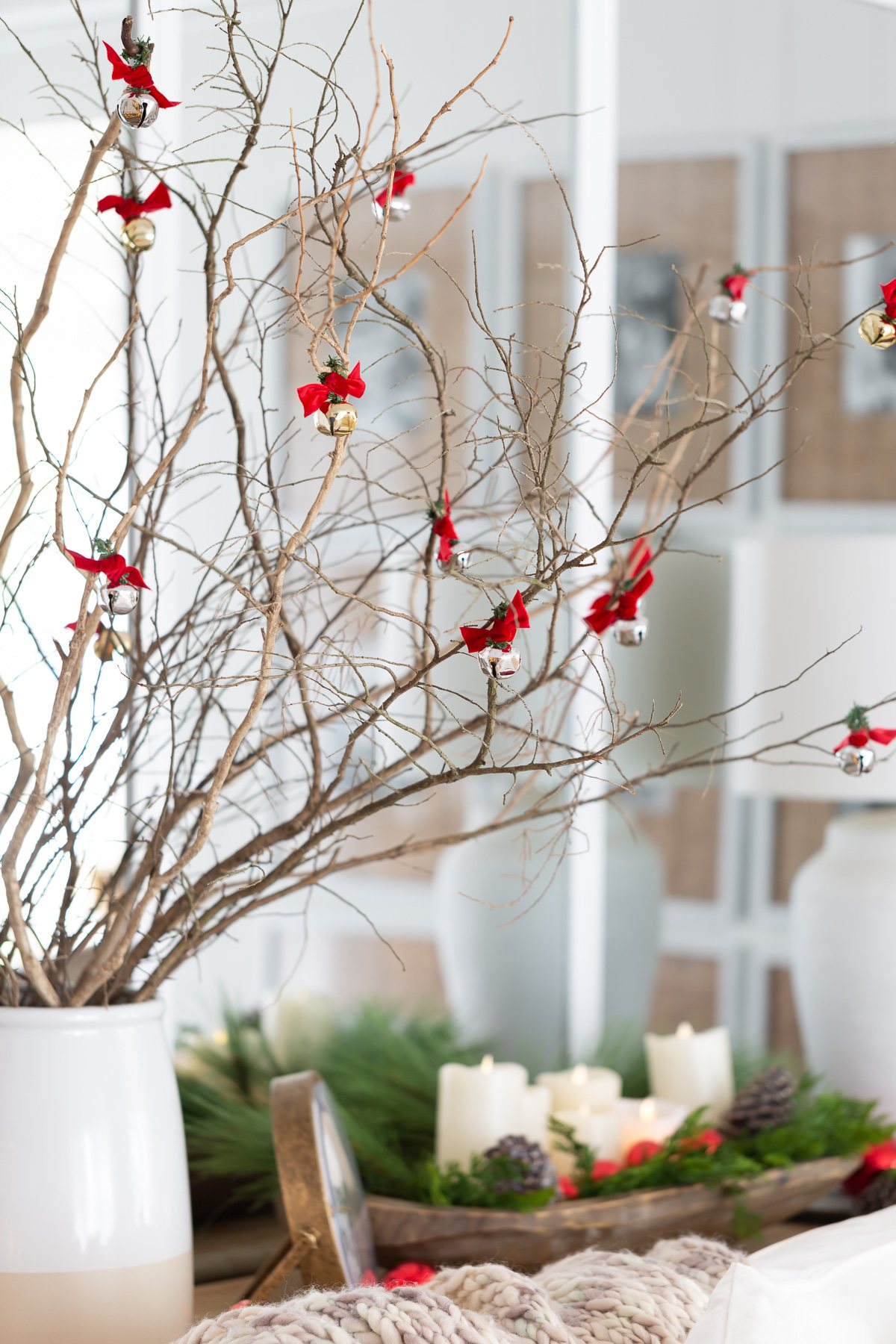 white battery operated candles in a dough bowl and branches with jingle bells