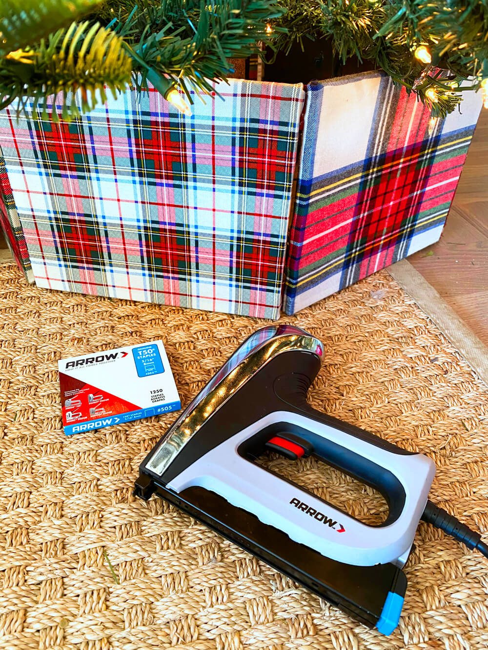 Plaid DIY tree collar with Arrow staple gun and staples on the floor nearby.