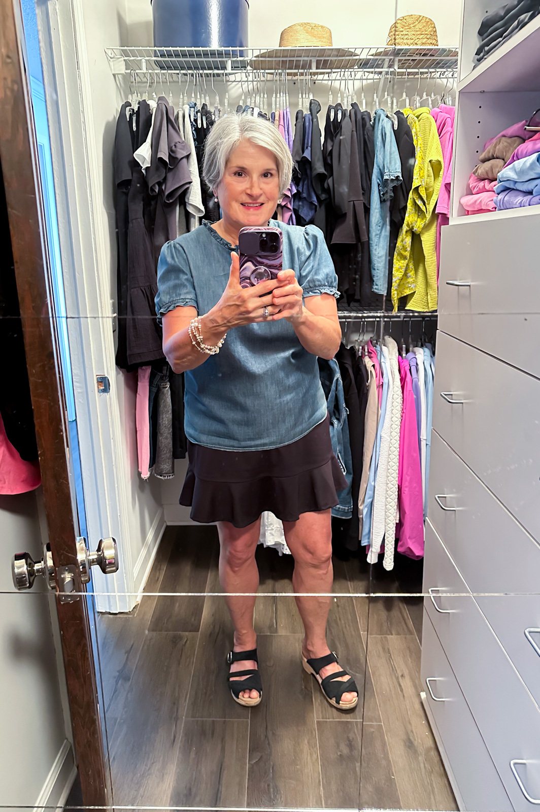 Blogger, Diane Henkler standing in her clothes closet after cleaning and organizing it top to bottom.