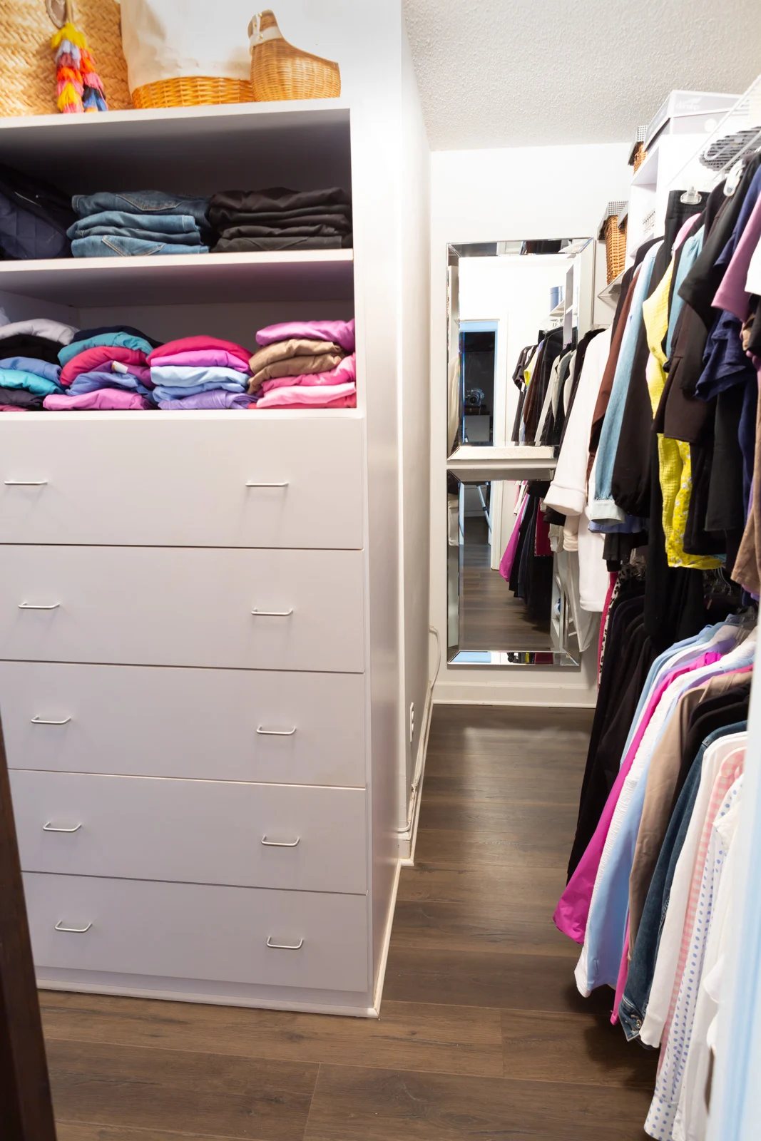 Full look into a walk in closet after cleaning it out and reorganizing the clothes and items in it.