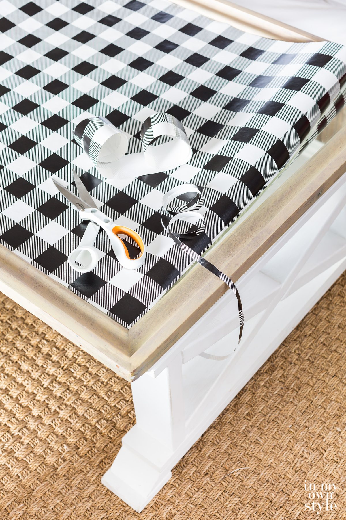 Black and white check gift wrap being cut to fit table top.