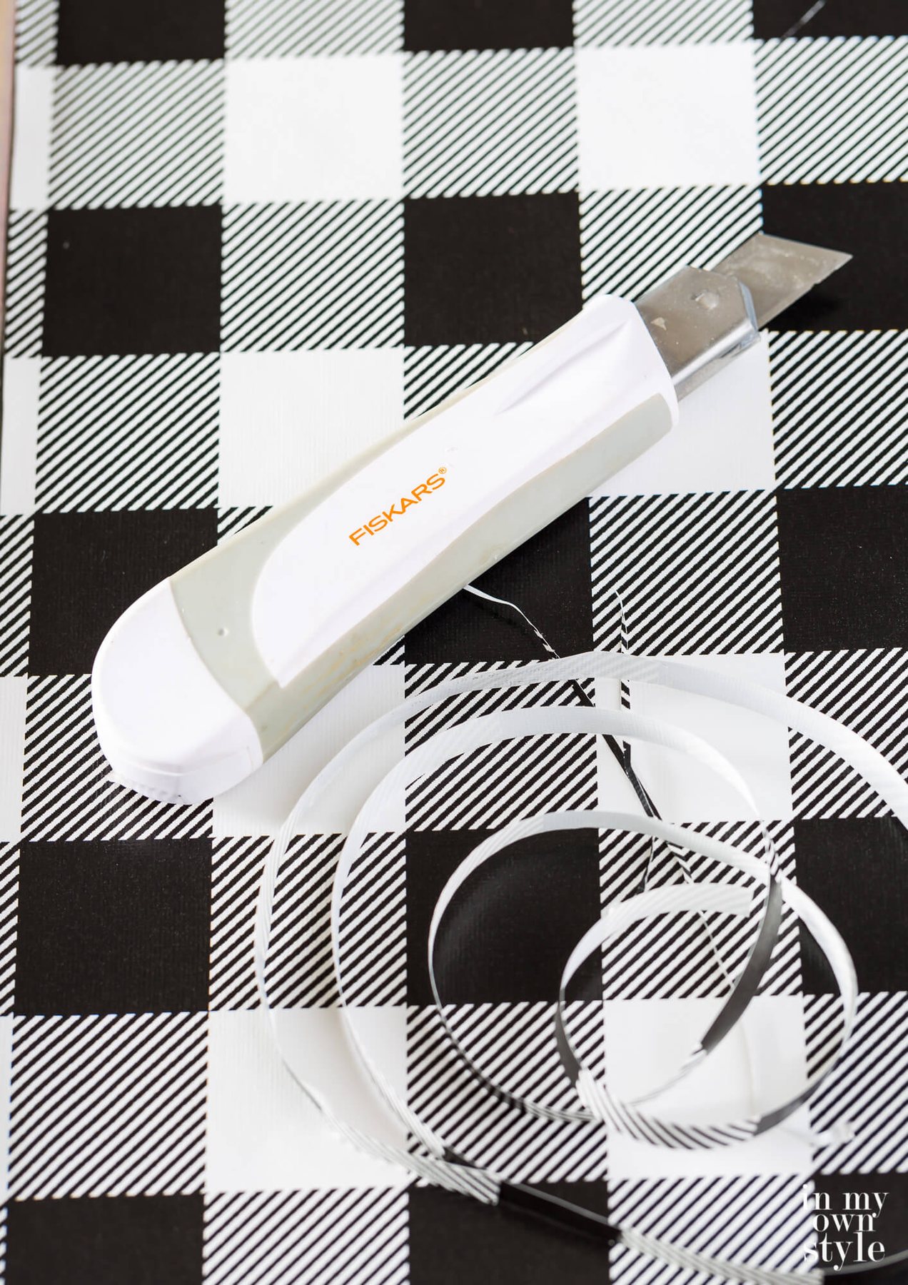 Fiskars craft knife on black and white check gift wrap.