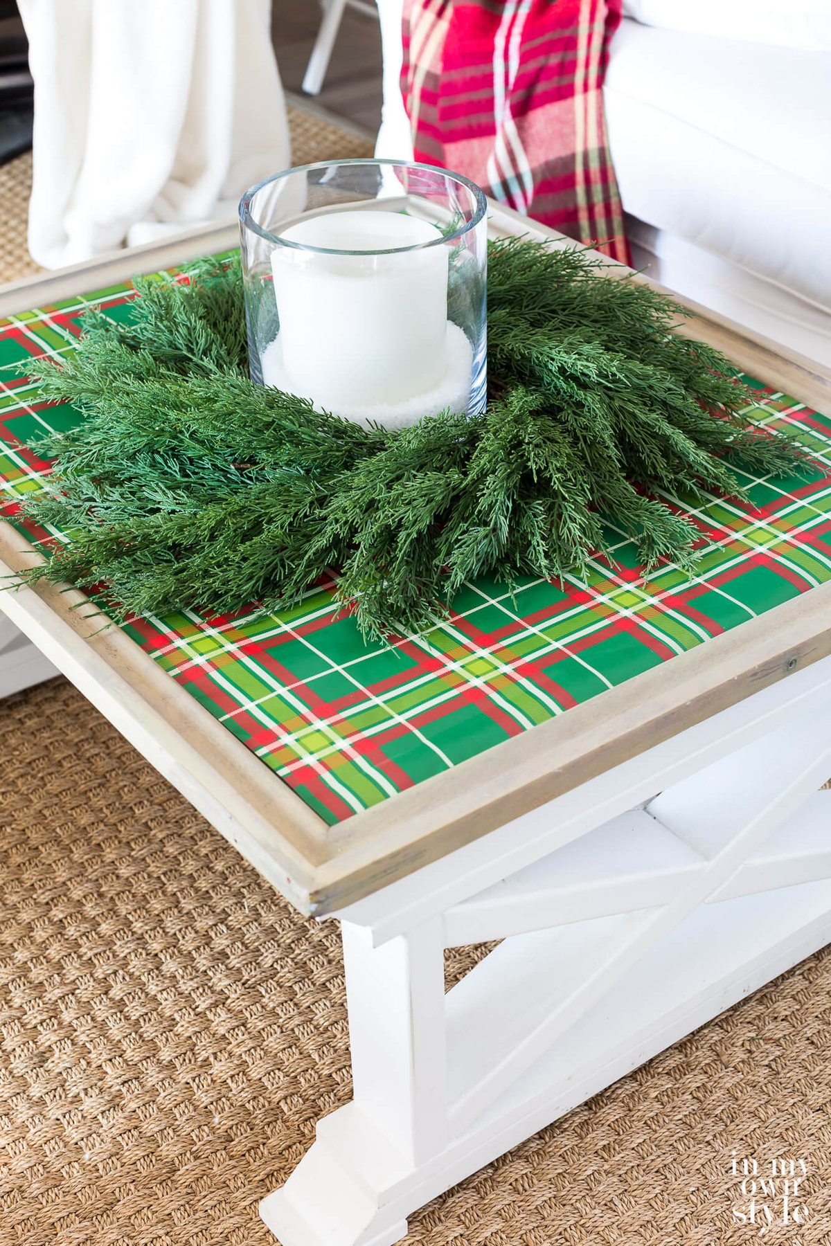 Coffee table covered with green plaid gift wrap, wreath and candle.