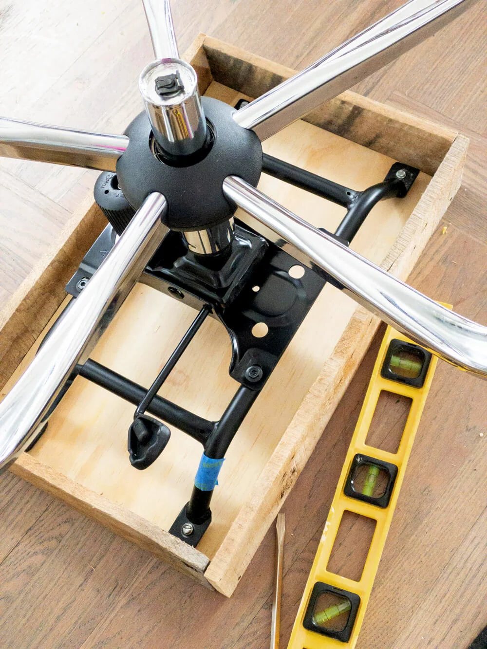 Attaching the base of an office chair to a wood box to make to hold a file folder organizer.