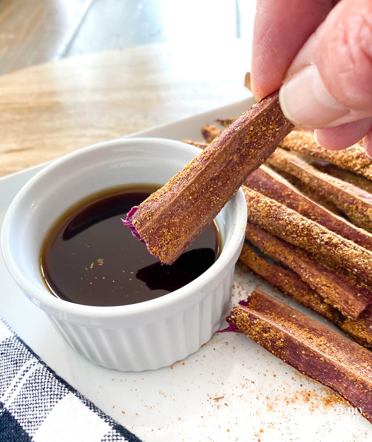Dipping a baked purple sweet potato fry into malt vinegar.