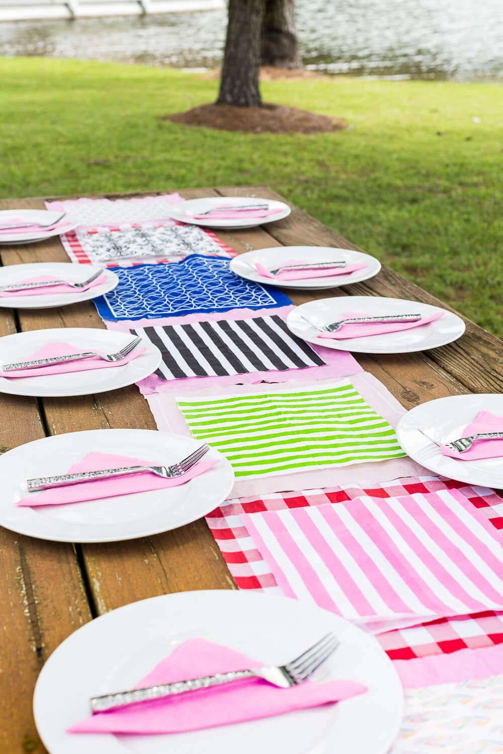 White and pink and green striped paper napkins made into an outdoor picnic table runner.