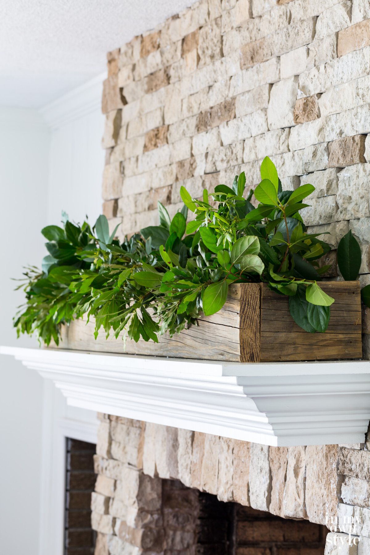White mantel on stone fireplace with wood planter box filled with greenery is my go to summer decorating idea.