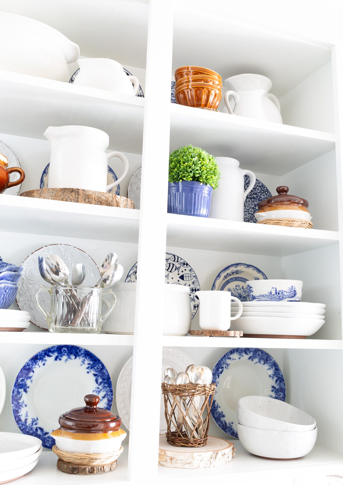 Open white shelves in kitchen decorated with blue, white and brown items.