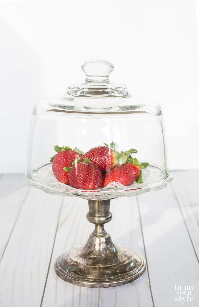 glass dome over a pedestal plate of strawberries