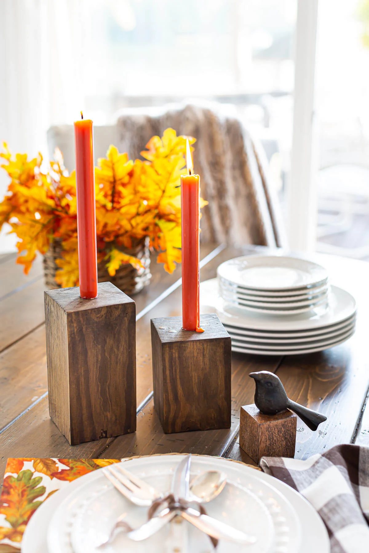 Completed DIY Wooden Candle Holders on a dining table with dark orange taper candles.