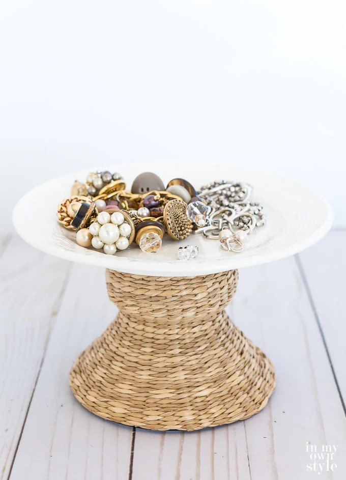 Jewelry on a plate on top of a wicker candle holder