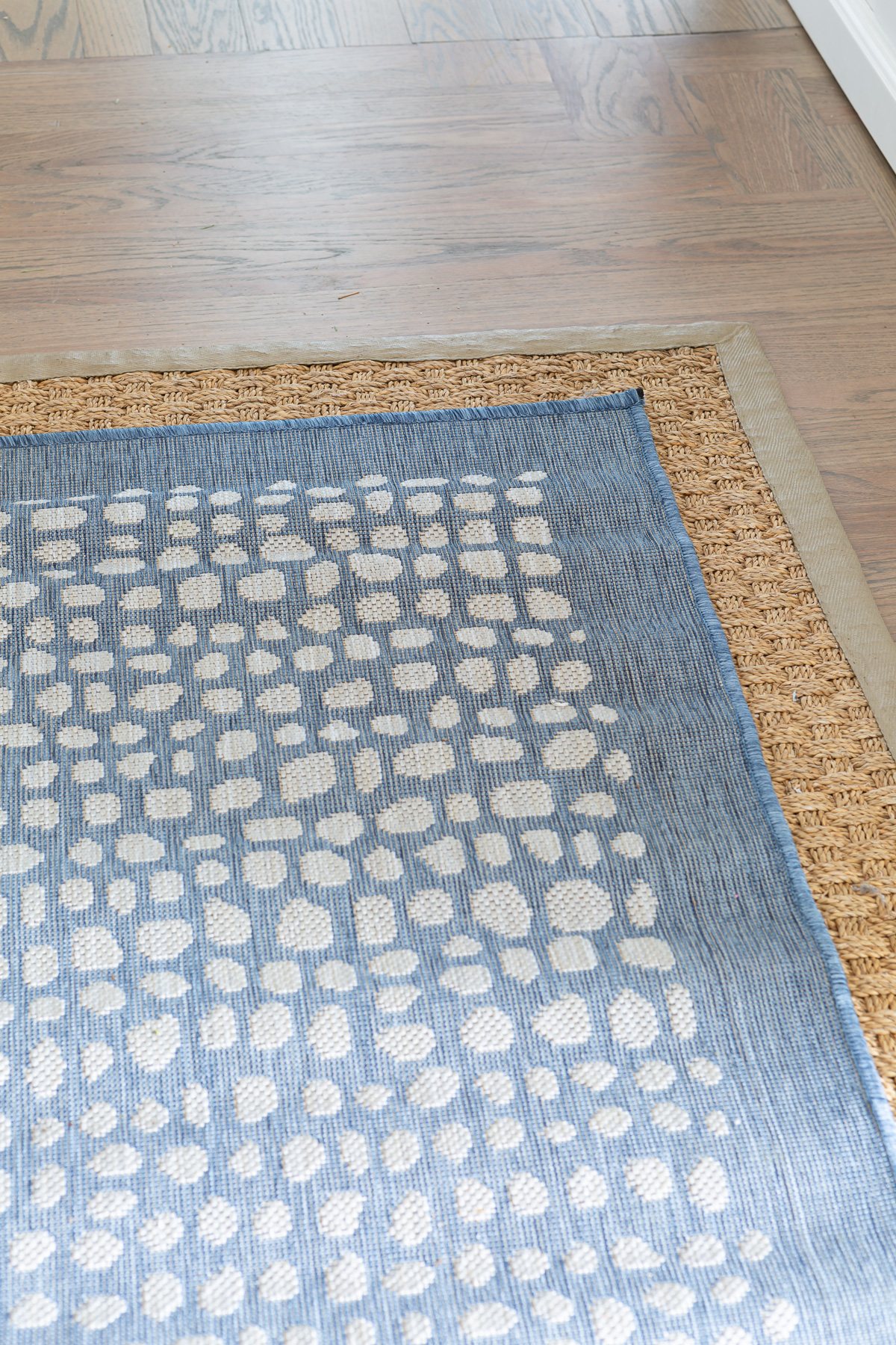 two area rugs layered one on top of the other on a hardwood floor.