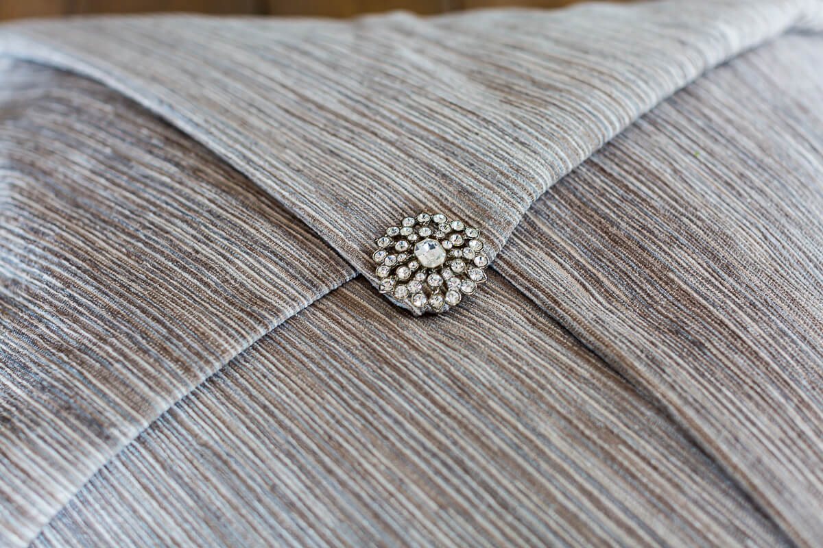 Rhinestone pin that secures a decorative throw pillow on a pillow.
