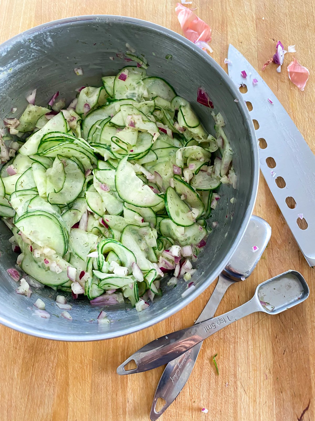 cucumber salad being made in a mixing bowl