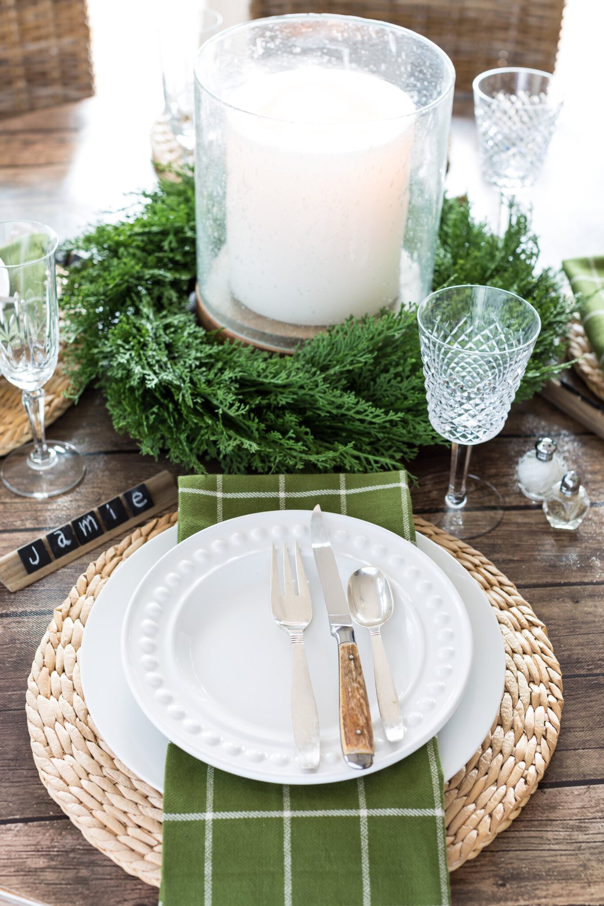 Dark wood look dining table cover with large bubble glass candle in center of table.