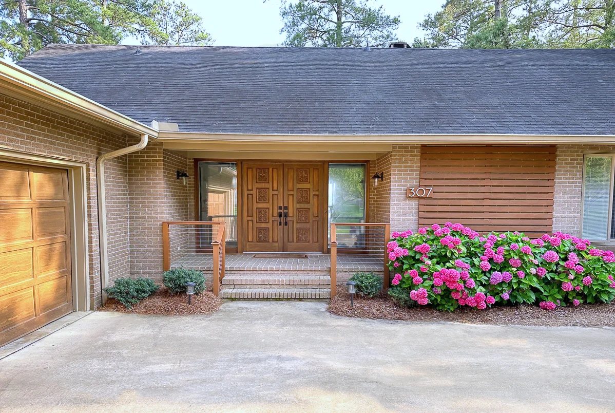 Completed DIY cable railing on a brick front porch of a home.