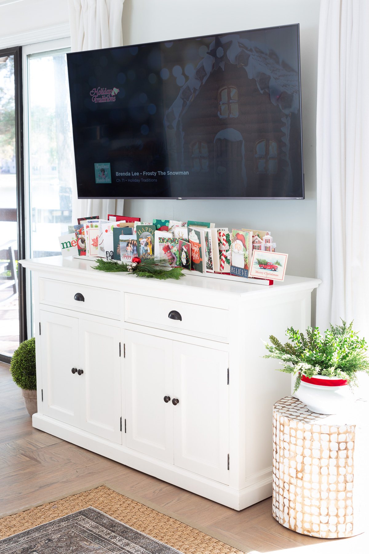 DIY Christmas card stand on a sideboard under a wall mounted TV.