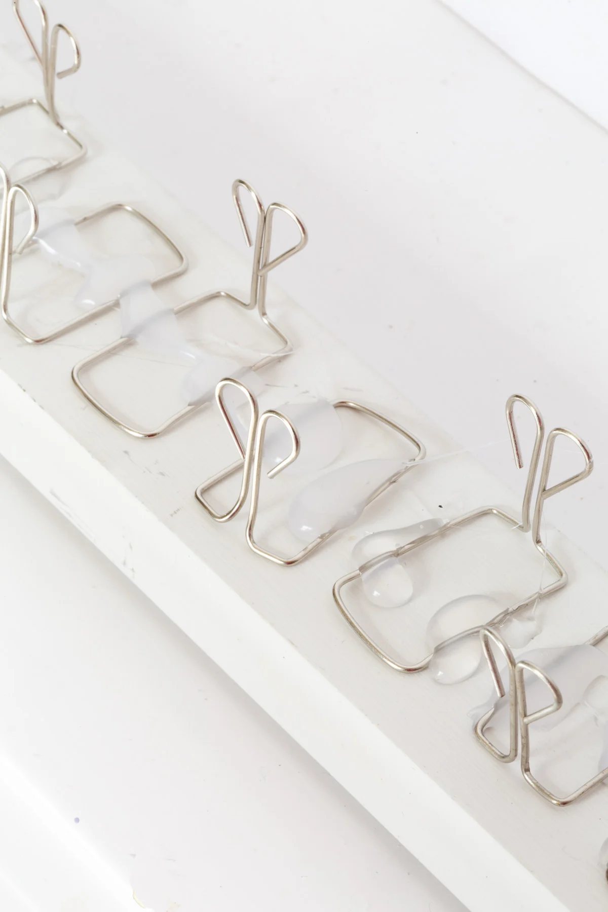 close up of owl style paper clips attached to scrap wood to make a holiday card holder.