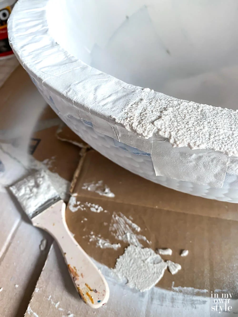 Spreading layer of stucco patch on bowl with a paint brush.