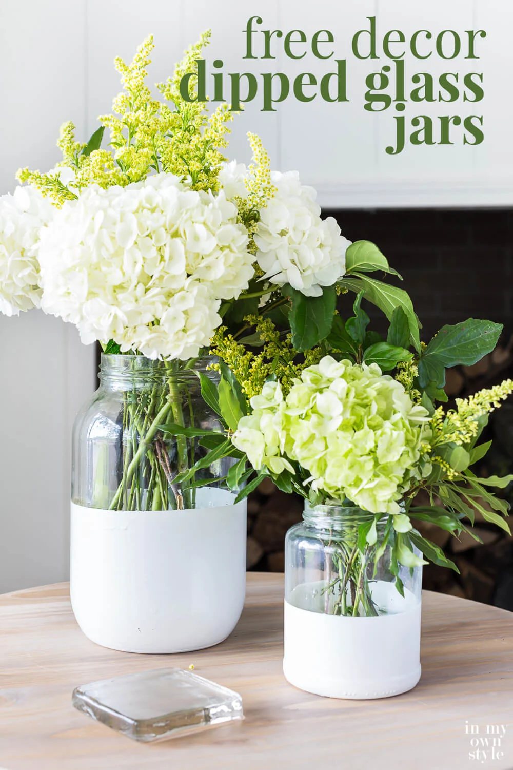 Two glass vases with white painted bottoms filed with white and light green flowers.