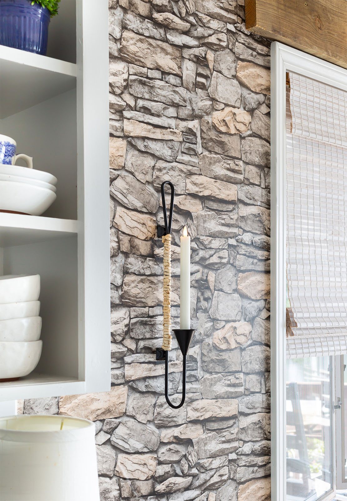 Black metal and natural cord wrapped candle sconce hanging on wall in kitchen.